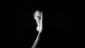 Ein Schwarz-Weiß-Foto eines Mannes, der sein Gesicht mit der Hand bedeckt und das Konzept der Strafmündigkeit darstellt.