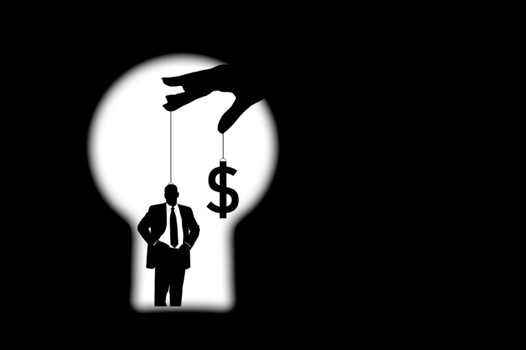 Ein Silhouettenbild einer Person in Anzug und Krawatte, die von einer riesigen Hand durch Fäden gesteuert wird. Ein weiterer Faden ist an einem Dollarzeichen befestigt, das an „Verrückte Verbote“ erinnert. Die Szene ist von der Umrisslinie einer Glühbirne vor schwarzem Hintergrund eingerahmt.